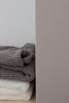 A stack of wool sweaters on the shelf. Grey and white sweater. Warm and cozy. Stock Photos