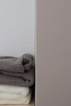 A stack of wool sweaters on the shelf. Grey and white sweater. Warm and cozy. Stock Photos
