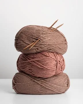 Stack of wool yarn skeins with knitting needles on white background. Minimali Stock Photos