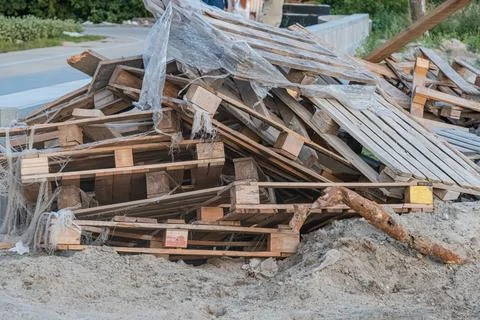 Stack of worn wooden crates, partially covered with torn plastic sheeting, ag Stock Photos