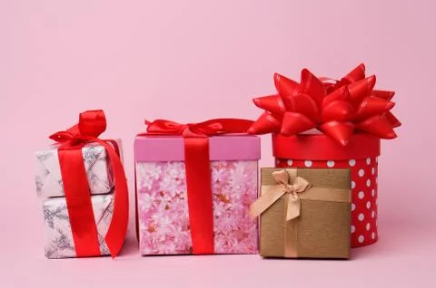 Stack of wrapped gifts with knotted bows on a pink background Foto stock