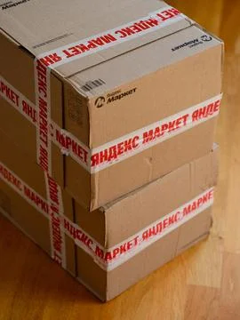 A stack of Yandex Market cardboard boxes on a parquet floor. Stock Photos