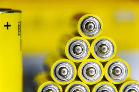 Stack of yellow AA batteries close up abstract coloured background Foto stock