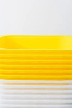 Stack of yellow and white recycled plastic containers with part of wall 스톡 사진