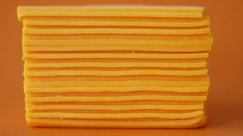 Stack of Yellow Cheese Slices on Orange Background Stock Footage 288543649