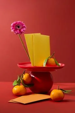 A stack of yellow envelopes and tangerines on a dish. Red background. Chinese Foto stock