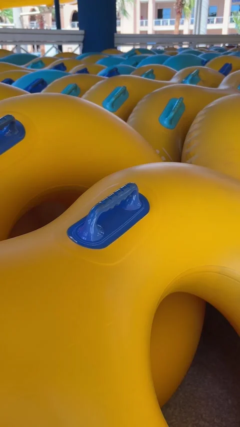 Stack of yellow inflatable rubber rings at a sunny outdoor water park Stock Footage 337137707