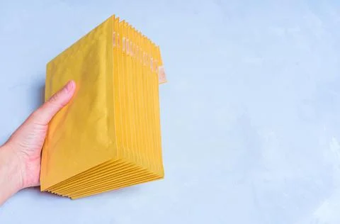 Stack of Yellow Padded Envelopes in Hand Foto stock
