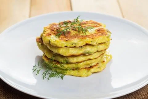 Stack of zucchini pancakes on white plate. Green vegetarian fritters. 스톡 사진