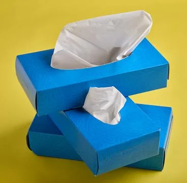 Stacked Blue Tissue Boxes on Bright Yellow Background Foto stock