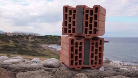 Stacked bricks with thermal insulation foam on rocky coast against ocean Stock Footage 265394886