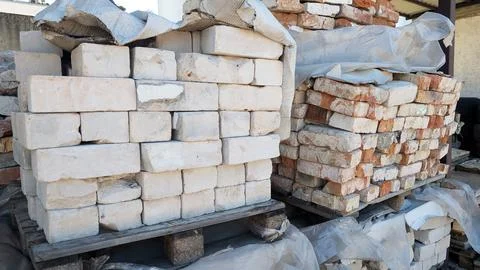 Stacked bricks in various colors and textures, arranged on wooden pallets Stock Photos
