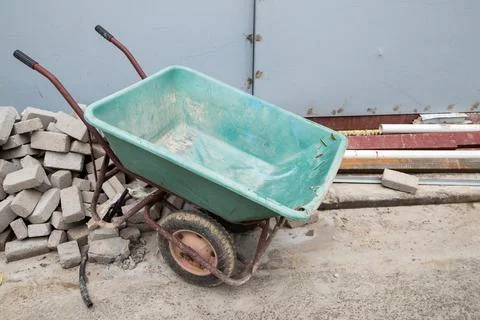 Stacked bricks with wheelbarrow in construction site Stockfoto's