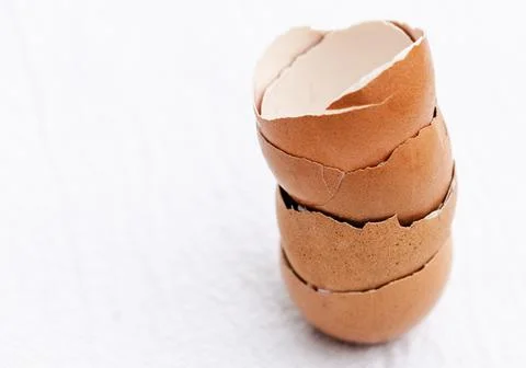Stacked brown eggshells on white background, copy space. Stock Photos