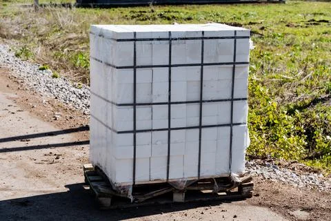 Stacked bundle of white construction bricks on a wooden pallet outdoors, se.. Stockfoto's