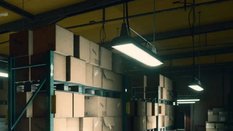 Stacked cardboard boxes in a warehouse with lights overhead Stock Footage 344845085