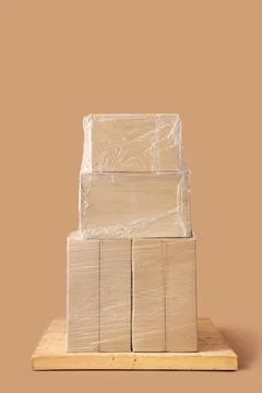 Stacked cardboard boxes wrapped in clear plastic on wooden pallet, shipping a Stock Photos