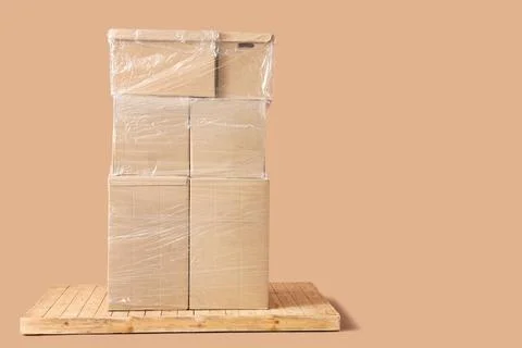 Stacked cardboard boxes wrapped in plastic on wooden pallet for shipping and  Stock Photos