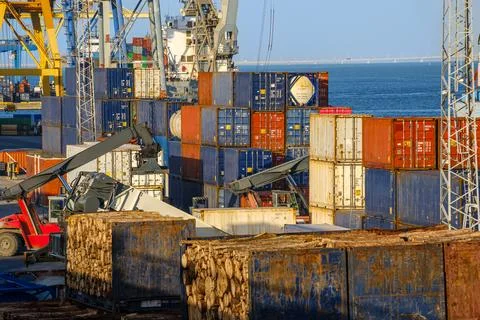Stacked cargo and flat rack containers, cranes at work on sunny day in port Stock Photos