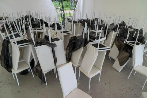 Stacked chairs resting upside down, covered with plastic sheets Foto stock