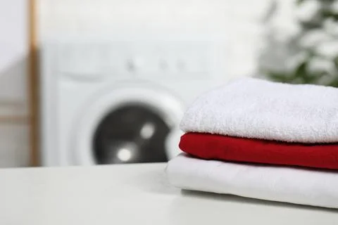 Stacked clean laundry on white table in bathroom, space for text Stock Photos