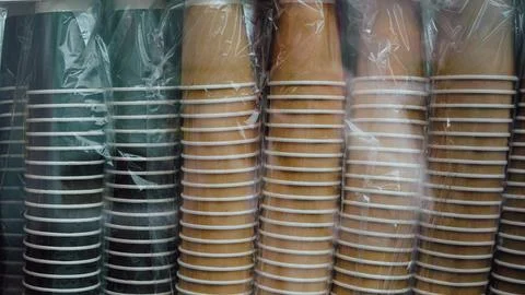 Stacked disposable cups in plastic wrap, various colors and sizes visible Stock Photos