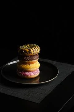 Stacked donuts on black plate with dramatic lighting Stock Photos