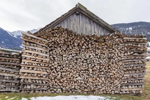 Stacked firewood logs in front of a rustic wooden shed Stockfoto's