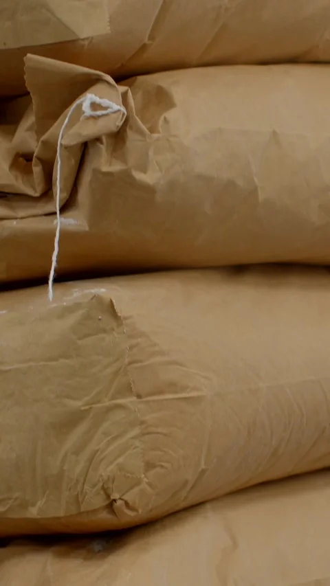 Stacked kraft paper sacks with hanging twine in vertical portrait storage scene Stock Footage 344573517