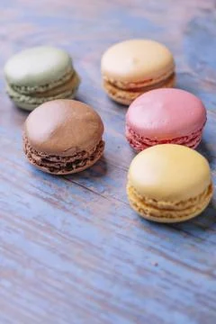 Stacked macarons of different flavors on an old wooden table. 스톡 사진