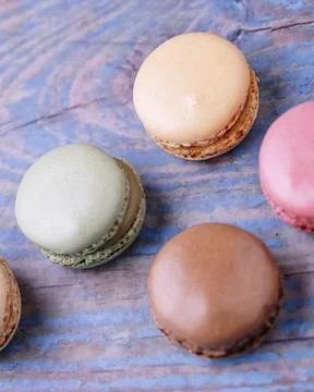 Stacked macarons of different flavors on an old wooden table. Stock Photos