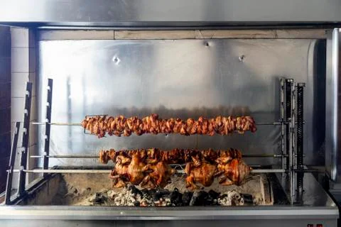Stacked meat roasting on rotating horizontal spit for souvlaki Stock Photos