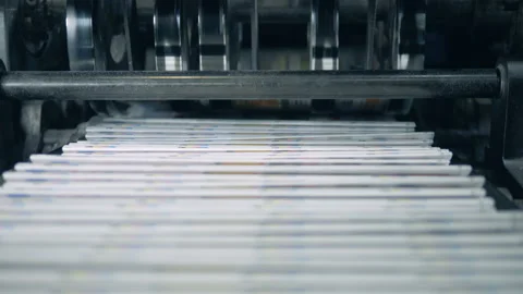 Stacked newspaper on automated conveyor, typography facility. Stock Footage