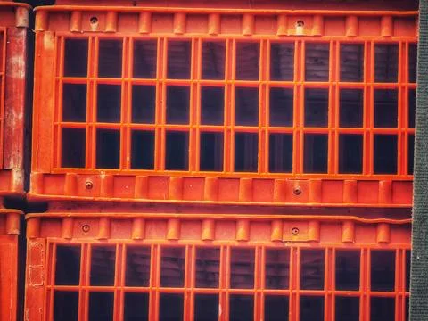 Stacked orange plastic crates create a geometric grid pattern with a strong s Stock Photos