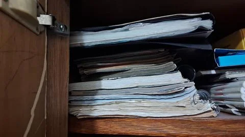 Stacked paper documents organized inside a dark wooden storage cabinet shelf Stock-Fotos