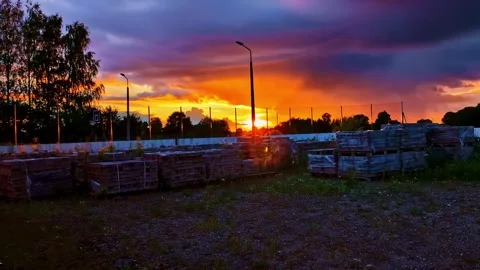 Stacked Paving Bricks on pallets in yard under fiery orange sunset sky Vídeo Stock 323078198