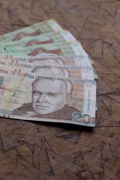 Stacked peruvian banknotes of different denomination on the brown surface Foto stock