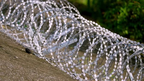 Stacked Razor Wire Coils Recede Along Concrete Barrier, Wide Shot Stock-Footage 344121175