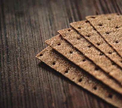 Stacked rectangular rye crispbread crackers resting on a rustic dark wooden.. 스톡 사진