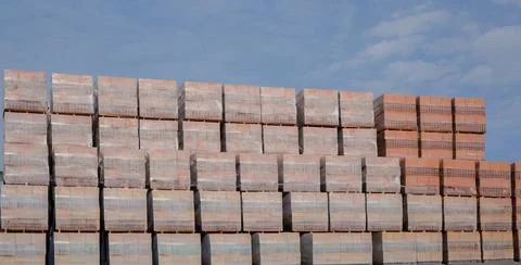 Stacked red bricks stored on pallets for construction use Stock Photos