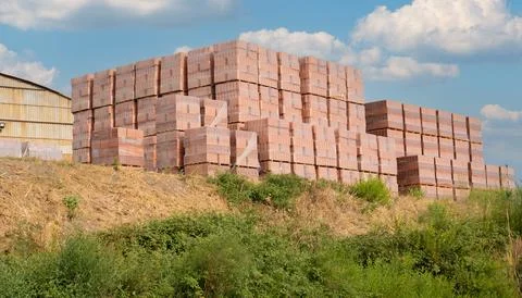 Stacked red bricks stored on pallets for construction use Stock Photos