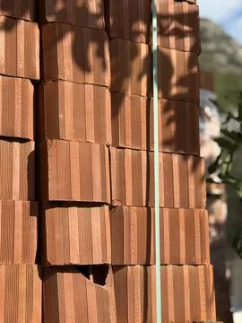 Stacked red bricks in sunlight with shadows creating a textured background Stockfoto's