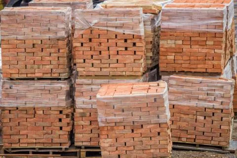 Stacked red clay bricks on pallets Foto stock