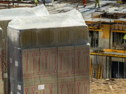 Stacked Rockwool insulation wrapped in plastic at a busy construction site with Stock Photos