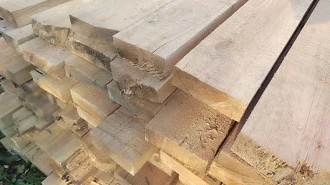 Stacked rough sawn timber planks with visible grain and uneven edges outdoors Stock Footage 347527006