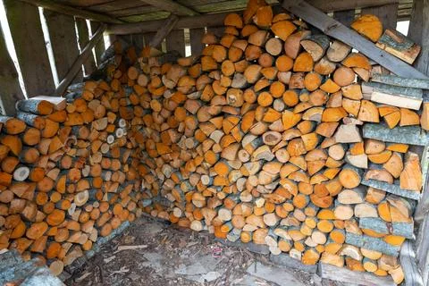 Stacked rows of split adler firewood in shed Stock Photos