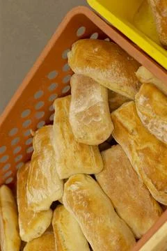 Stacked rustic bread rolls in orange bakery crate with flour dusted crusts bread Stockfoto's