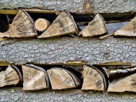 Stacked split firewood between barked logs Stock Photos