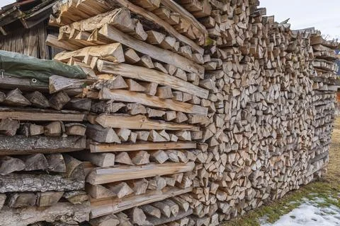 Stacked split firewood logs outside a rustic mountain hut Photos