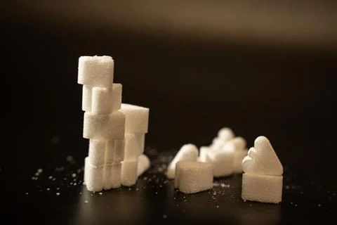 Stacked sugar cube tower with scattered heart shaped sugar pieces and sparkling Stock Photos